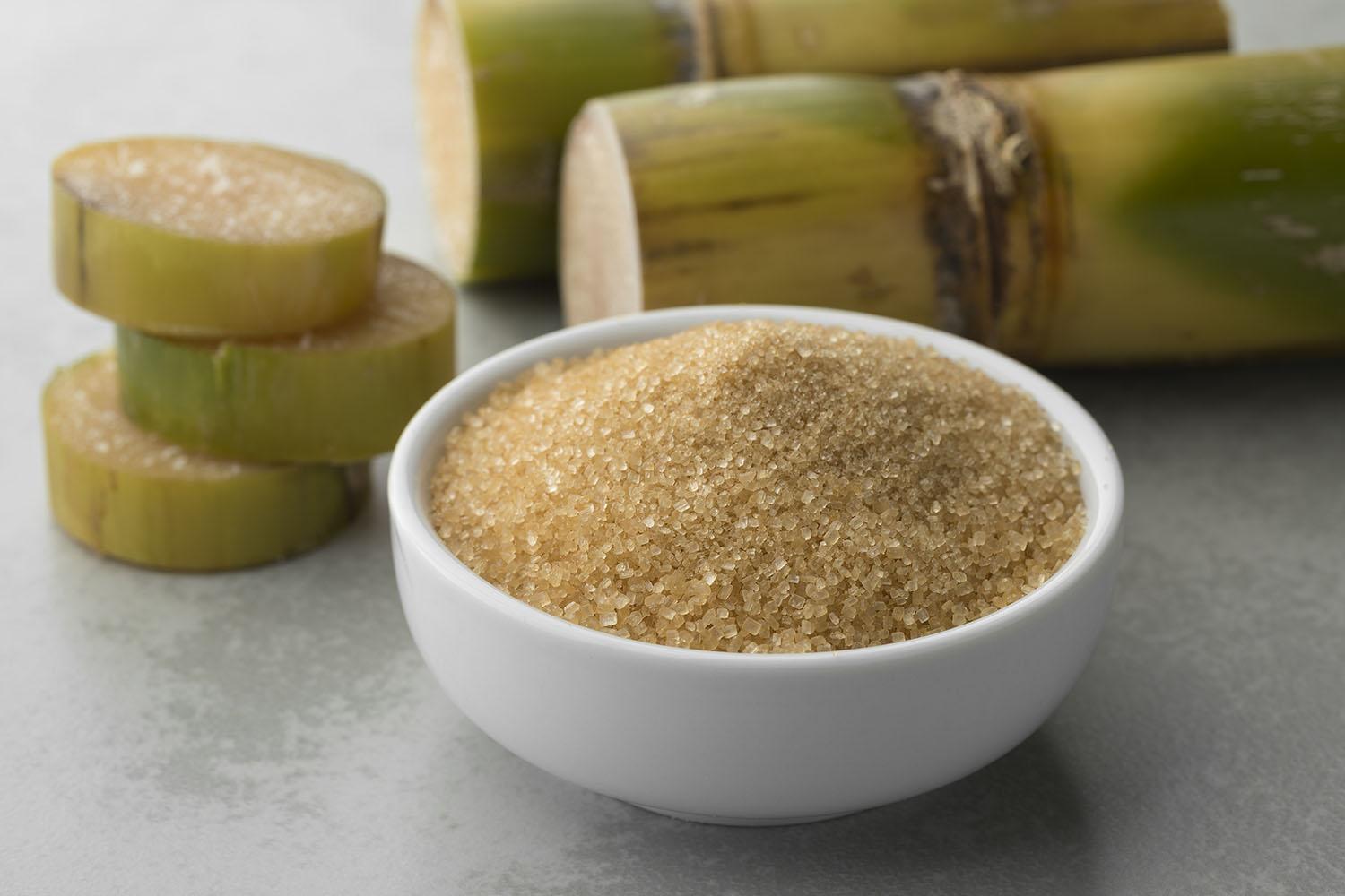 Raw sugar crystals with sugar cane